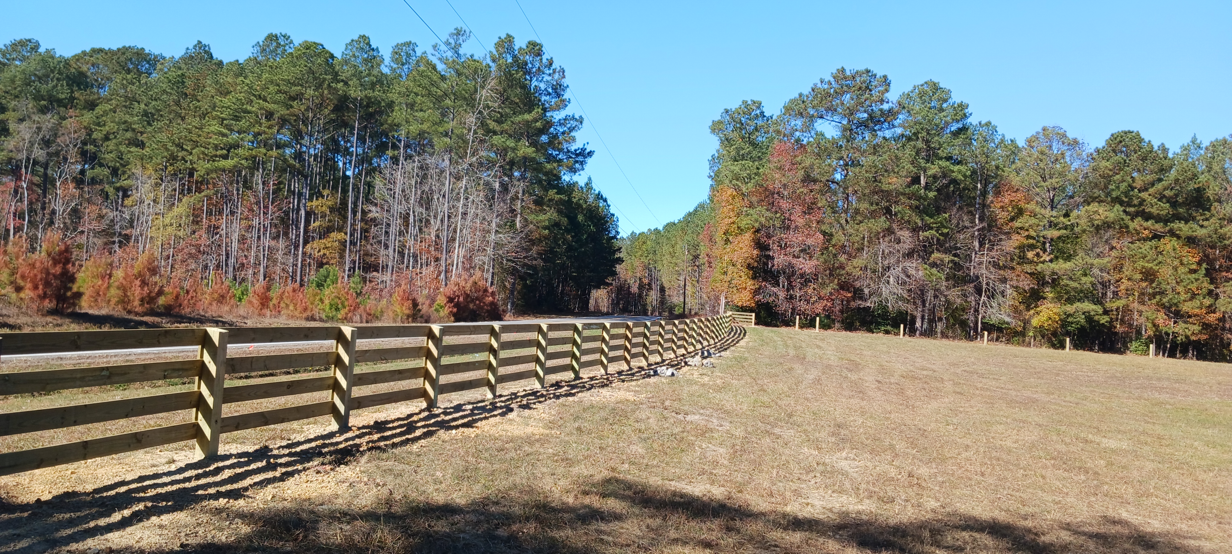 Long horizontal wood fence installed across open Virginia property.